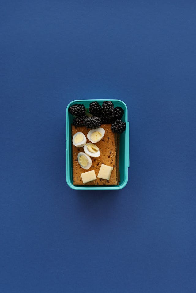 Blackberries, eggs, cheese, and crackers in a food prep container