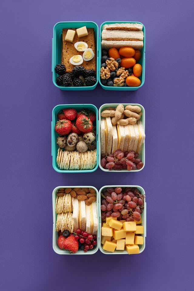 Six food prep containers with tomatoes, cheese, and grapes.